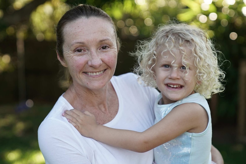 A mother holds a child on her hip.