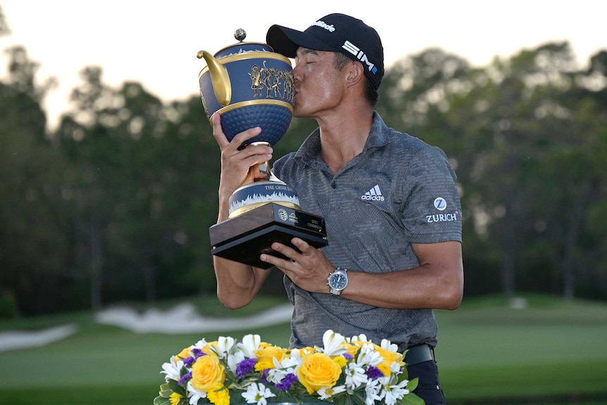 Male golfer kissing the championship trophy after winning a golf tournament