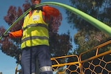 A worker feeds optic fibre cable into a pit during the NBN rollout.