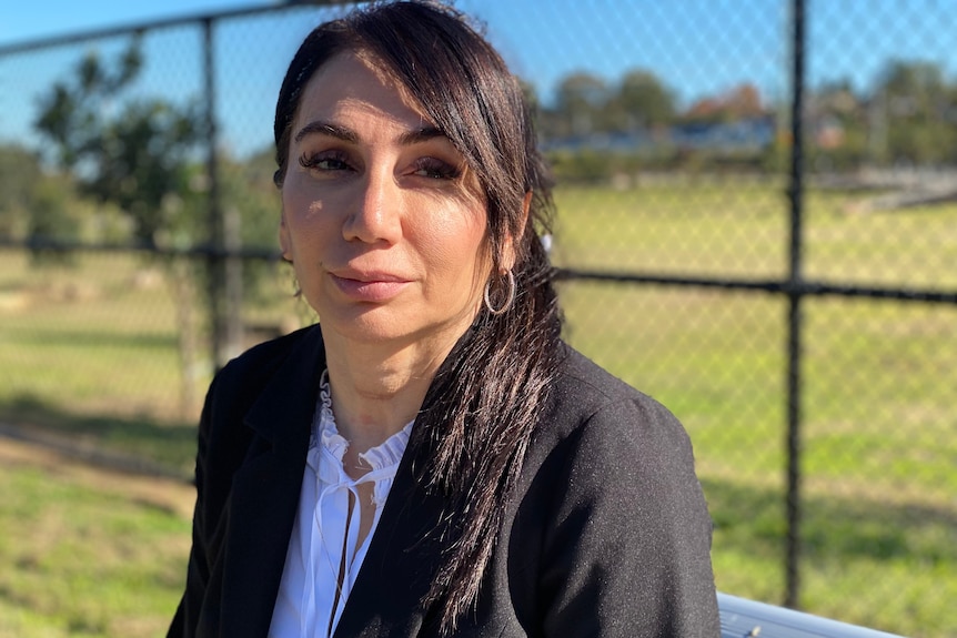 Tanya Petrus sits on a park bench and looks into the camera with a serious expression.