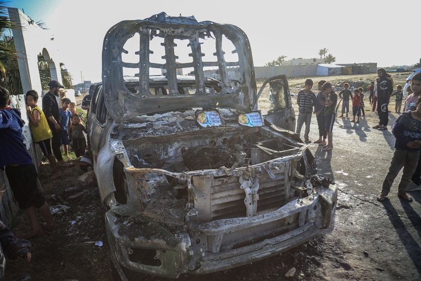 The wreckage of a car, with people surrounding it