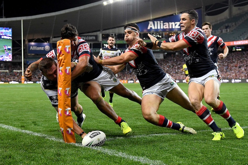 Kyle Feldt grounds the ball right in the corner as a number of Roosters defenders converge on him.