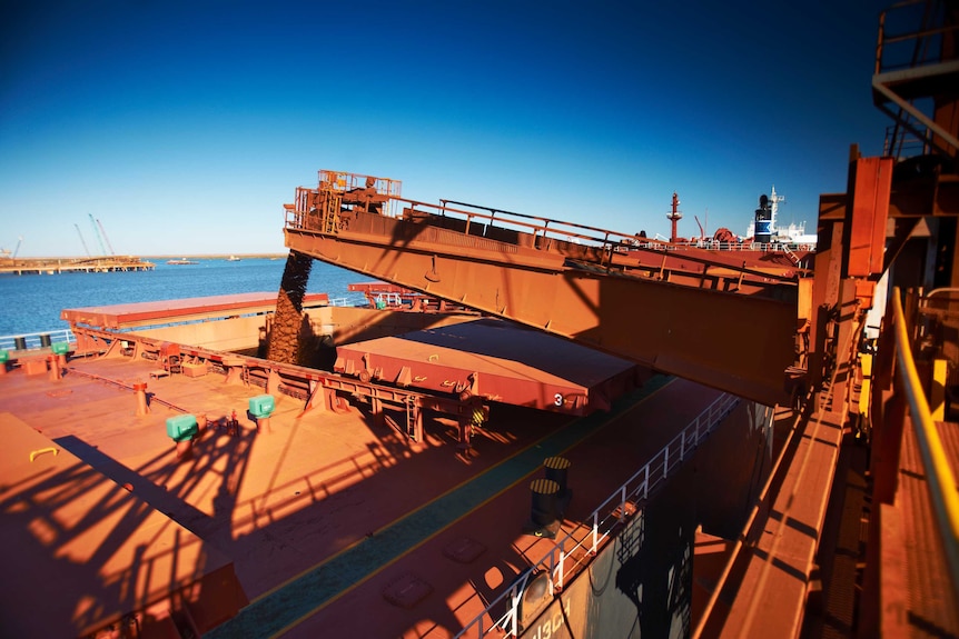 A wide shot of iron ore being loaded onto a ship in Port Hedland.