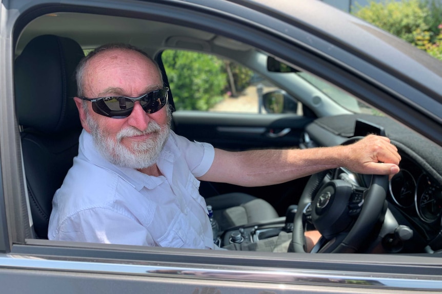 Andy Cawley sitting in the driver seat of a car wearing black sunglasses