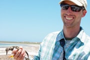 Man on beach holding young bird