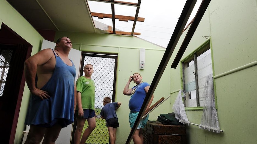 Scott Torrens (l) and his children look to where their roof once in Mourilyan, south of Innisfail