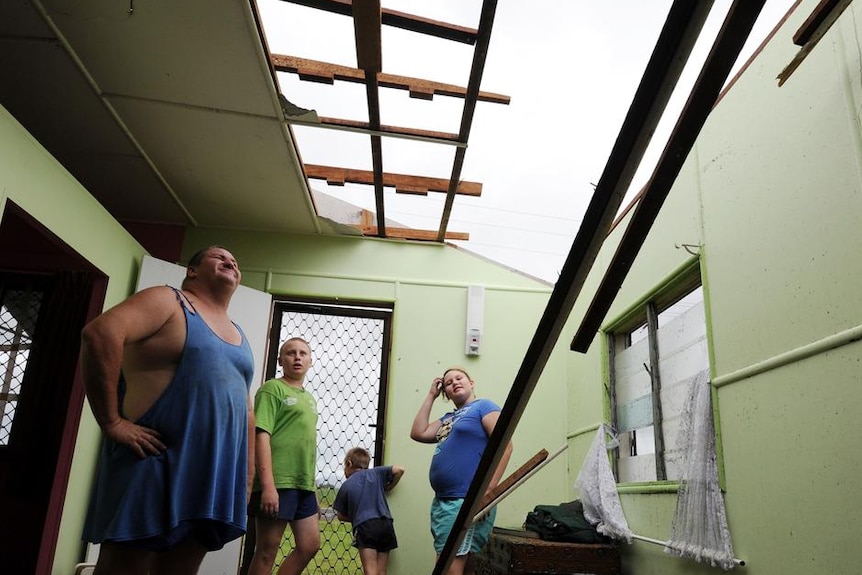 Scott Torrens (l) and his children look to where their roof once in Mourilyan, south of Innisfail