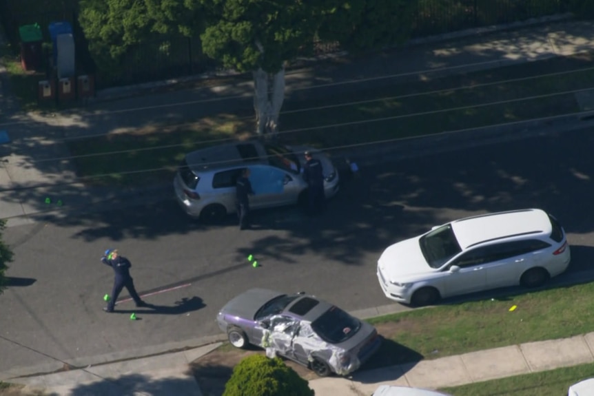Aerial shot of police near a parked car and another officer near green cones on the road. 