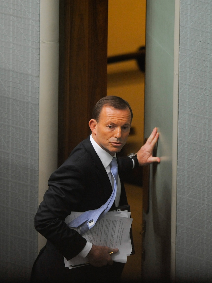 Opposition Leader Tony Abbott walks outside the parliamentary chamber after being ejected.