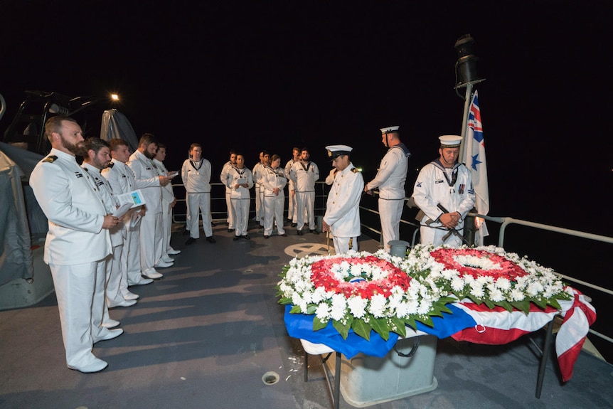 Sailors aboard ship take part in a ceremony commemorating the HMAS Perth.