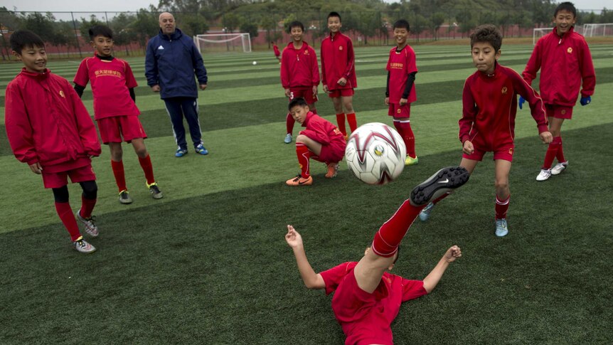 A group of Chinese children play soccer on the field.