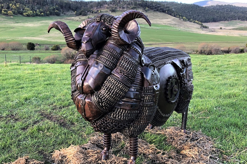 A lifelike looking ram made from old metal scraps and standing in a field