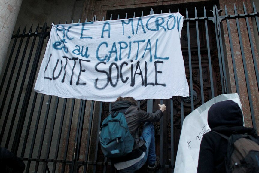 Demonstrators hold a banner reading "social struggle" after Macron's predicted win.