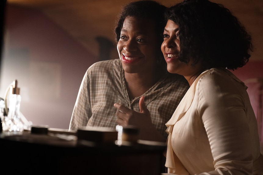 Fantasia Barrino and Taraji P. Henson in character as Celie and Shug, both smiling and looking away from the camera