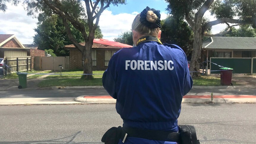 A forensics investigator takes a photo outside a house in Cranbourne North.