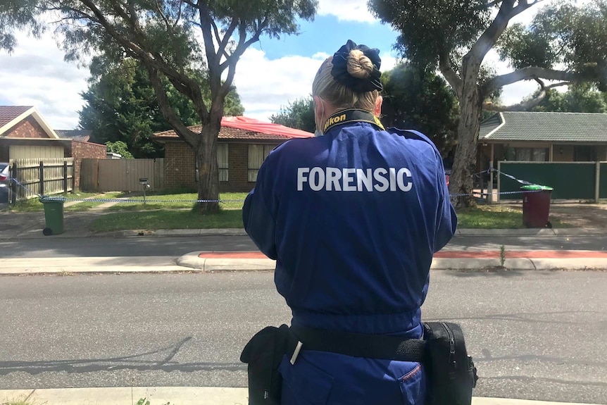 A forensics investigator takes a photo outside a house in Cranbourne North.