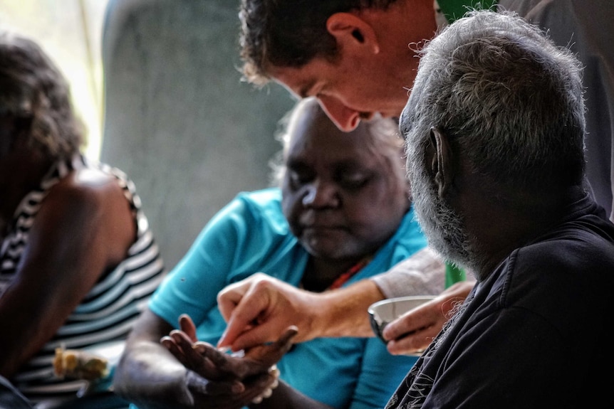 Father Pat Mara places a small piece of bread representing the body of Christ into the hand of a worshipper.