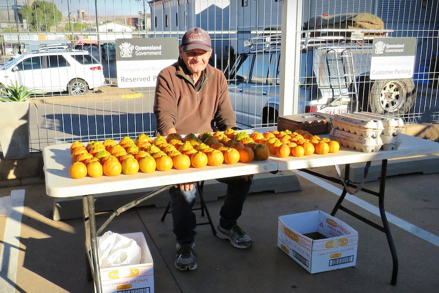 An older man sells oranges at a market stall