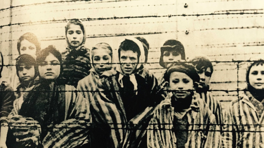 A group of children behind a barbed wire fence.