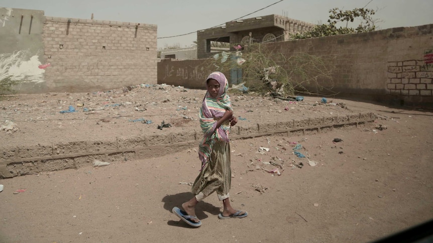 A girl walks alone on a street in al-Khoukha, Yemen.