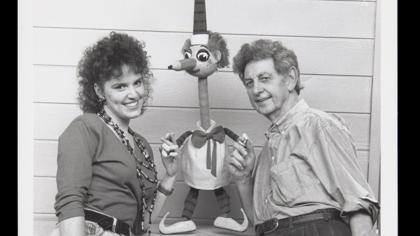 Puppet known as 'Mr Squiggle' standing in the middle of a man and a woman