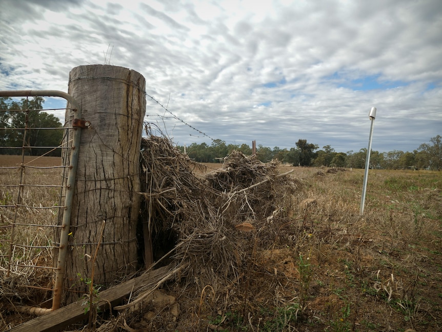 A broken fence covered in flood debris