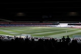 A view of the Melbourne Cricket Ground from under one of the grandstands, with fans in foreground.