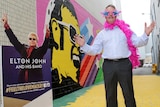 A man stands in front of a colourful mural