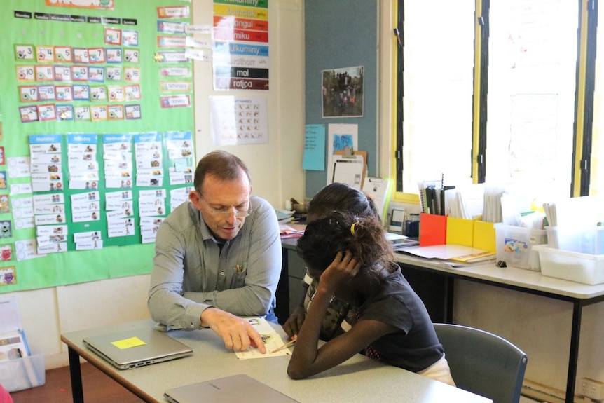 Tony Abbott sits with two children in a remote community.