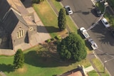An aerial shot shows police tape running from a church to a pole and from cars parked beside the church across a street.