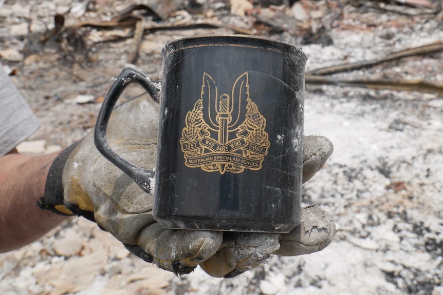 A gloved hand holding a special forces mug