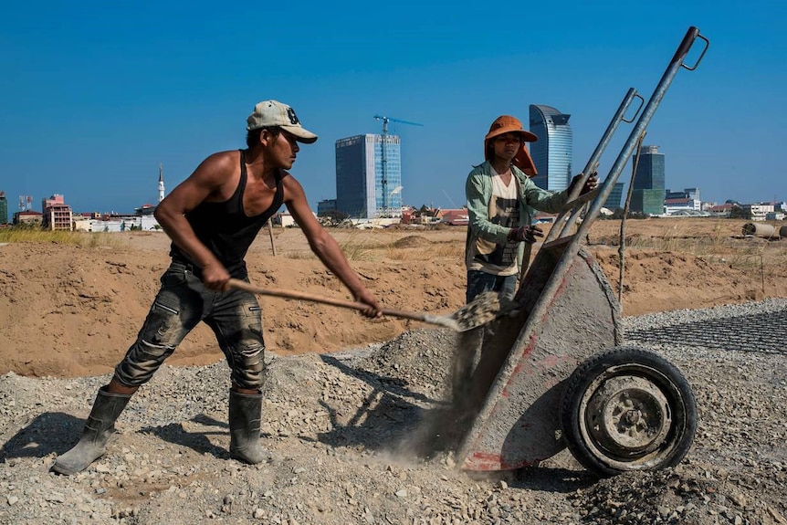 Two workers move gravel at a construction site in Phnom Penh.