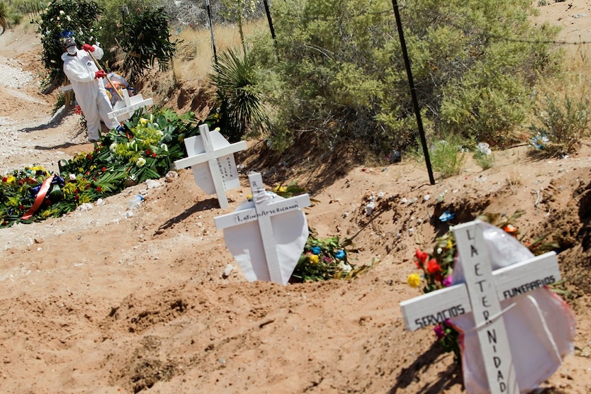 A cemetery worker fixes the grave after burying a coffin.