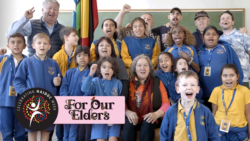 20 students, elders and teaching staff singing. The NAIDOC week and 'For Our Elders' logo overlaid.