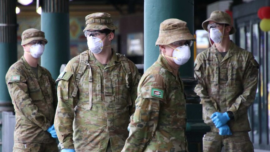 Four ADF officers wearing masks and blue gloves stand in a group.