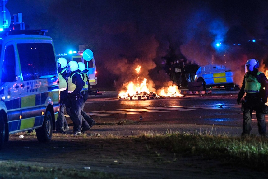 Riot police on the scene as smoke billows from burning tires and fireworks, as a few hundred protesters riot in the street.