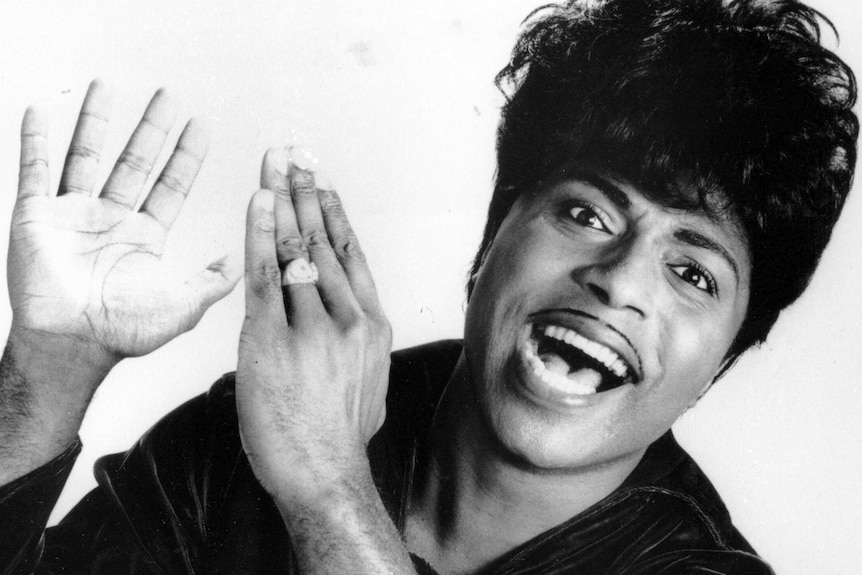A black and white photo of rock musician Little Richard with his hands about to clap.