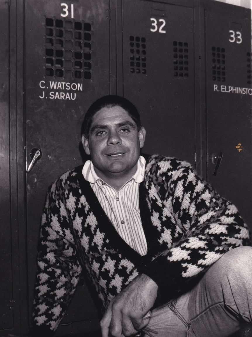 A man sits in front of lockers in a change room.