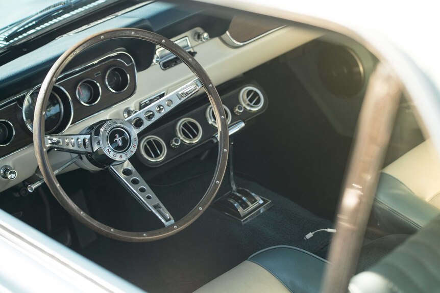 The steering column of a vintage Mustang as viewed through the window