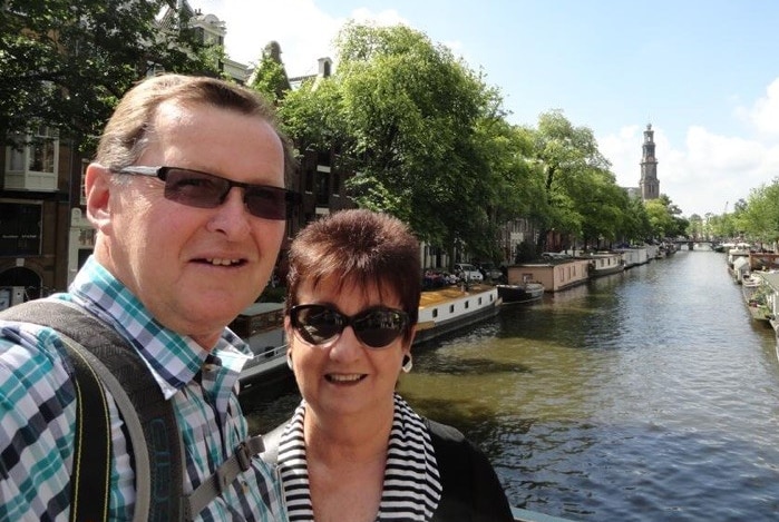 Howard and Susan Horder, both smiling and 63 at the time, stand on a bridge in Amsterdam during their holiday.