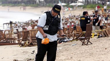 Investigation begins: forensic policeman surveys a bomb blast site at Jimbaran Beach