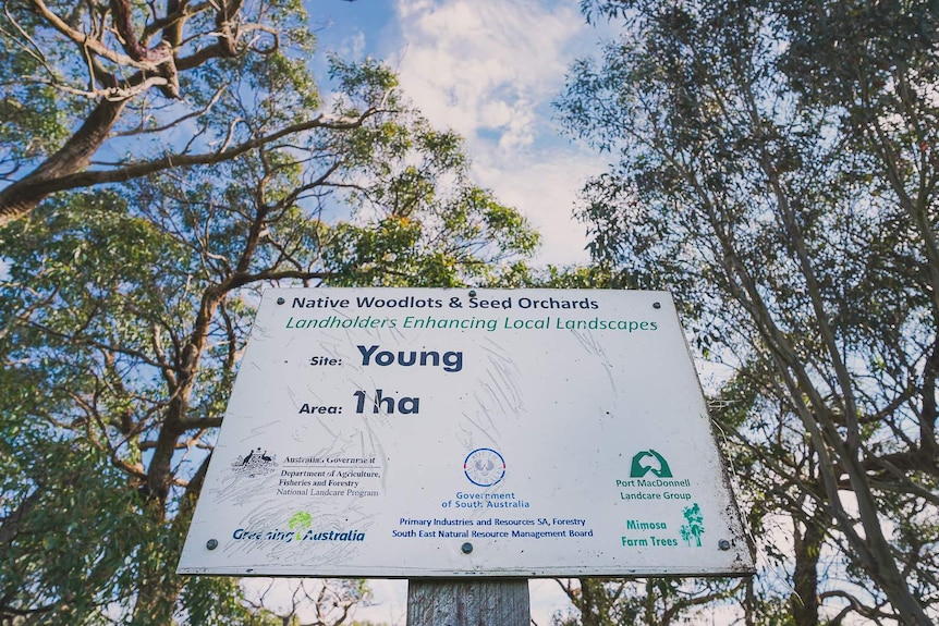 A government authorised sign surrounded by trees reads 'Landholders Enhancing Local Landscapes. Site, Young. Area, one hectare.'