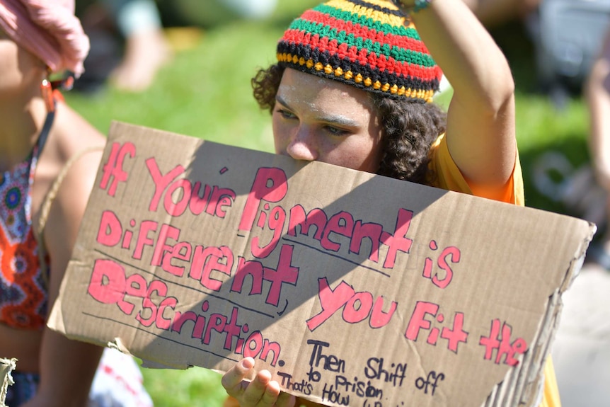 A person holds a sign that says 'if your pigment is different, you fit the description'