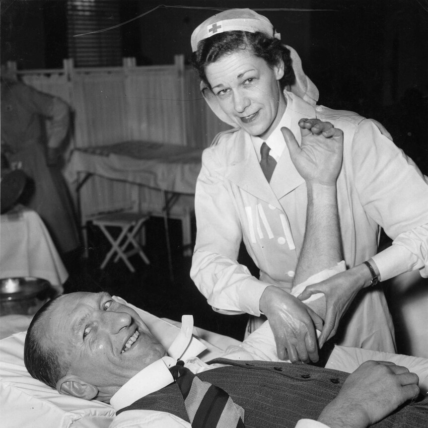 Black and white photo of a nurse administering blood to a man who is lying on a gurney.