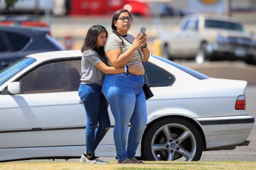 Two women react after a shooting in El Paso