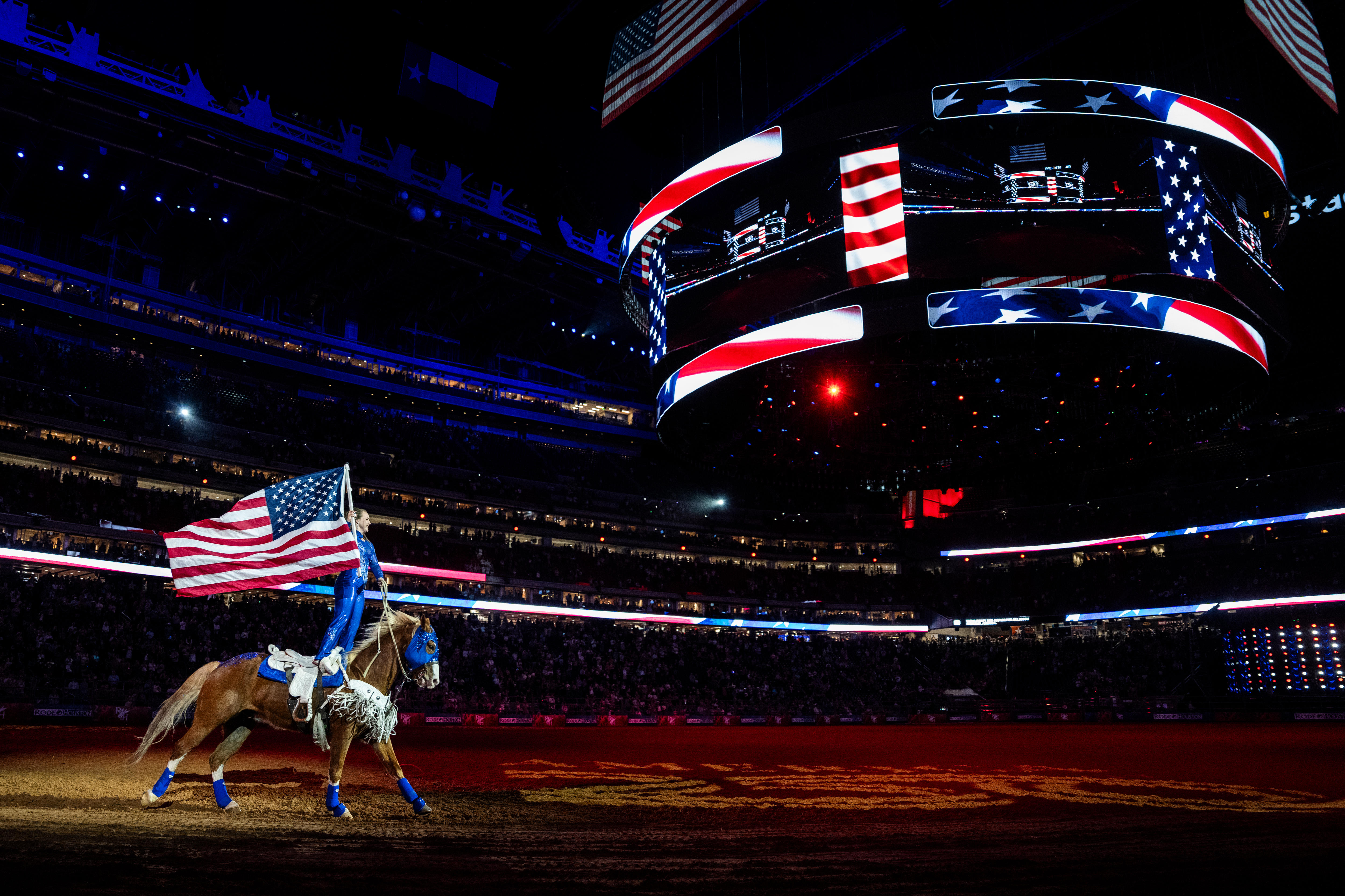 A woman rides a horse with a USA flag in her hand