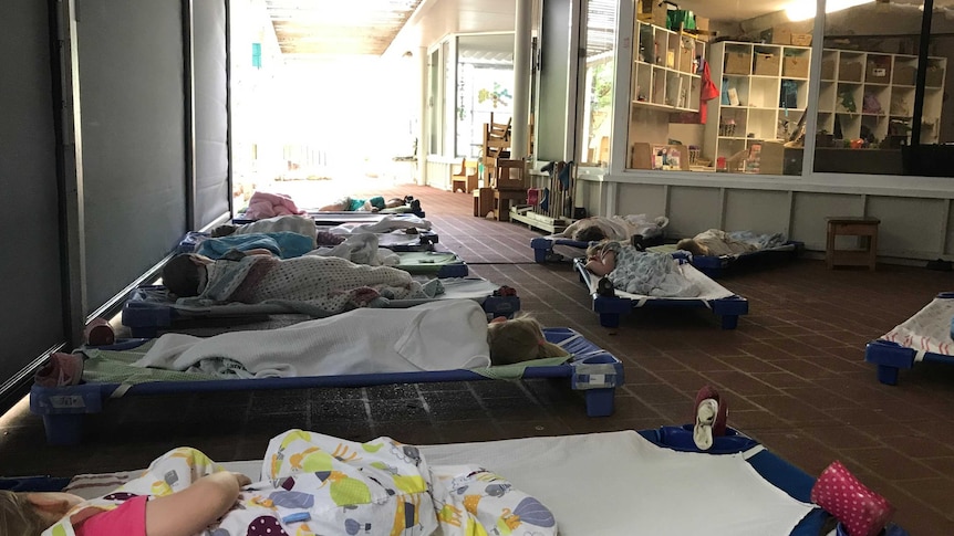 Children nap on an outdoor patio at a childcare centre