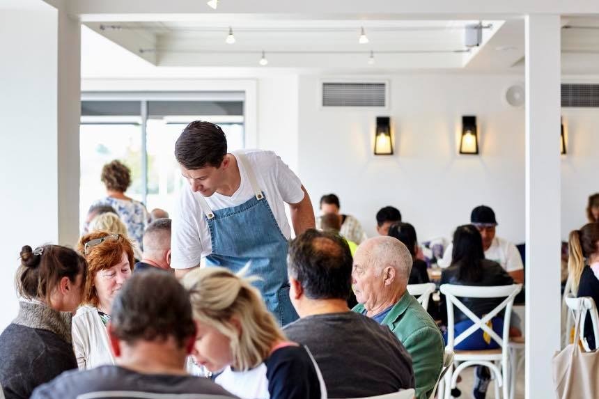 Mężczyzna serwujący jedzenie w stosunkowo zatłoczonej restauracji? 