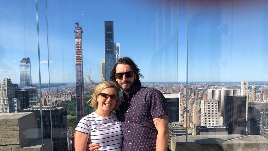 Alex Alewood and partner Jamie standing on a city rooftop.