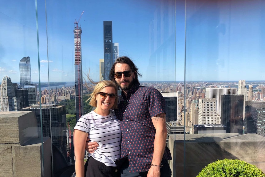 Alex Alewood and partner Jamie standing on a city rooftop.